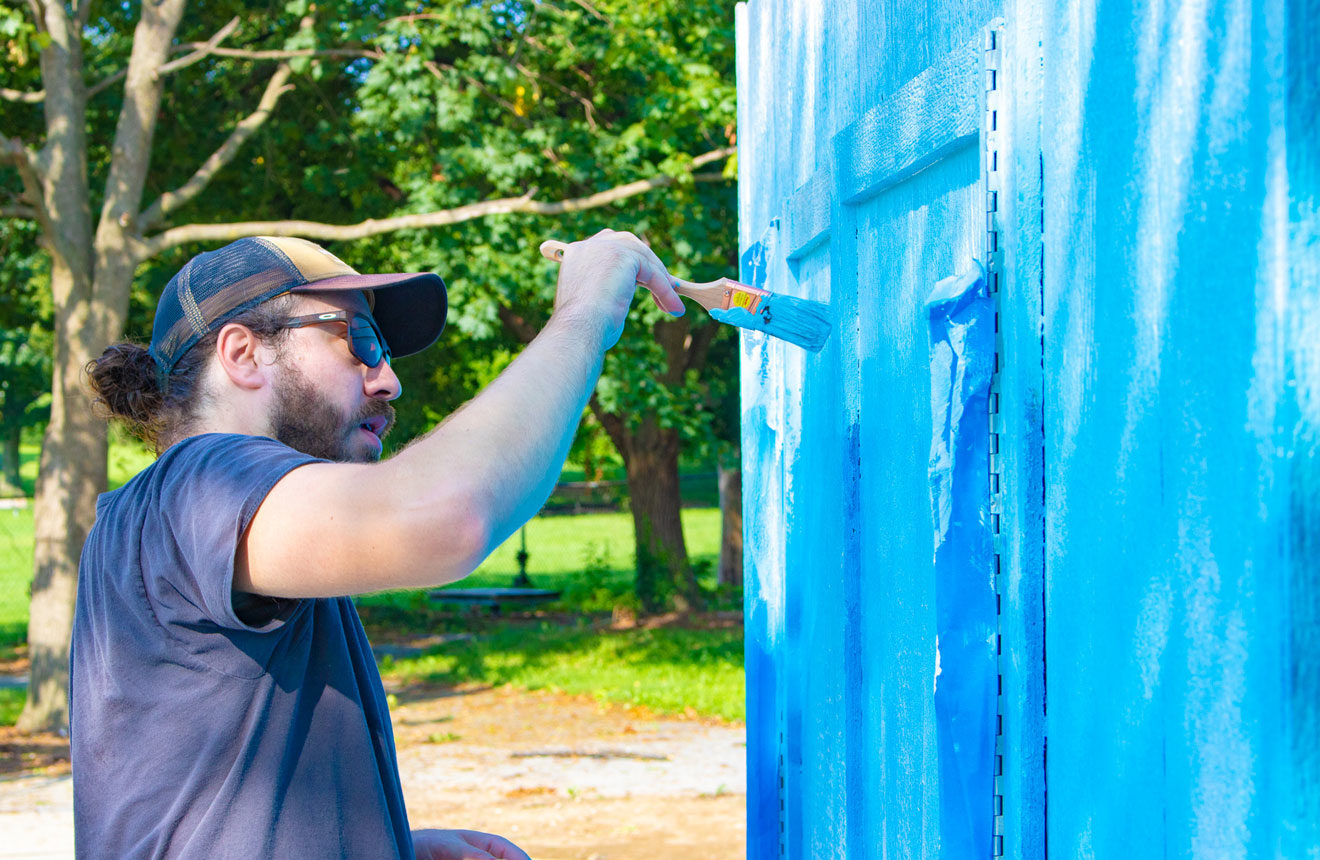 Gino painting blue shed at playground